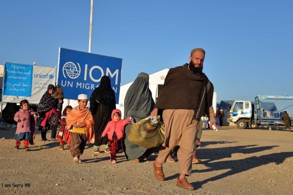 An Afghan family with young children walking through an IOM reception site